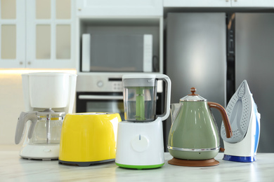 Photo of Set of modern home appliances on white marble table in kitchen