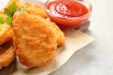 Photo of Tasty fried chicken nuggets on light grey table, closeup