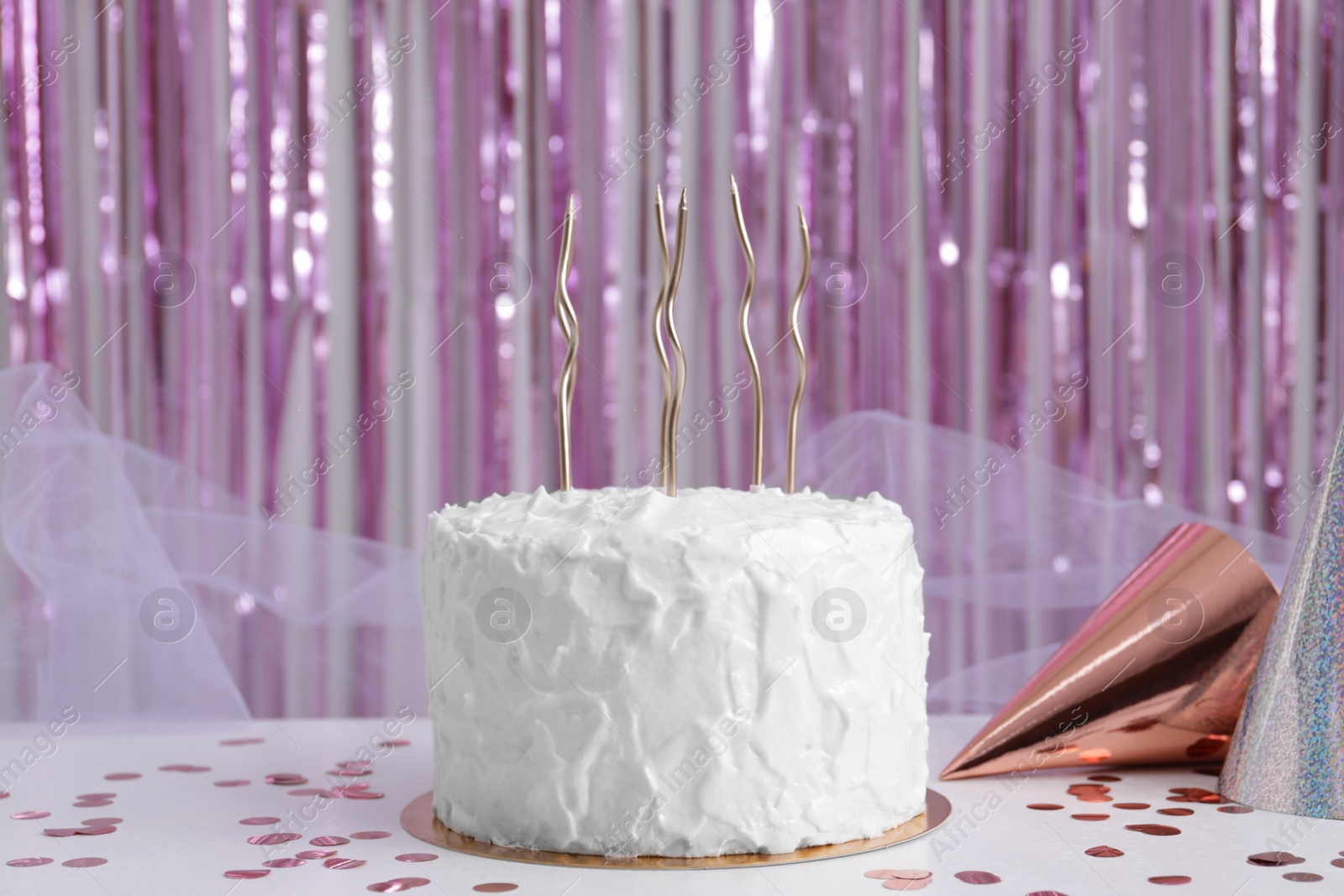 Photo of Delicious cake with candles and party hats on white table