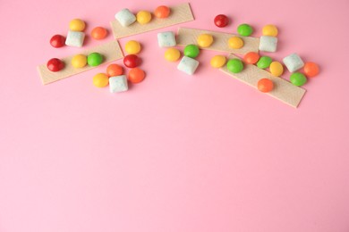 Photo of Different tasty chewing gums on pink background, flat lay. Space for text