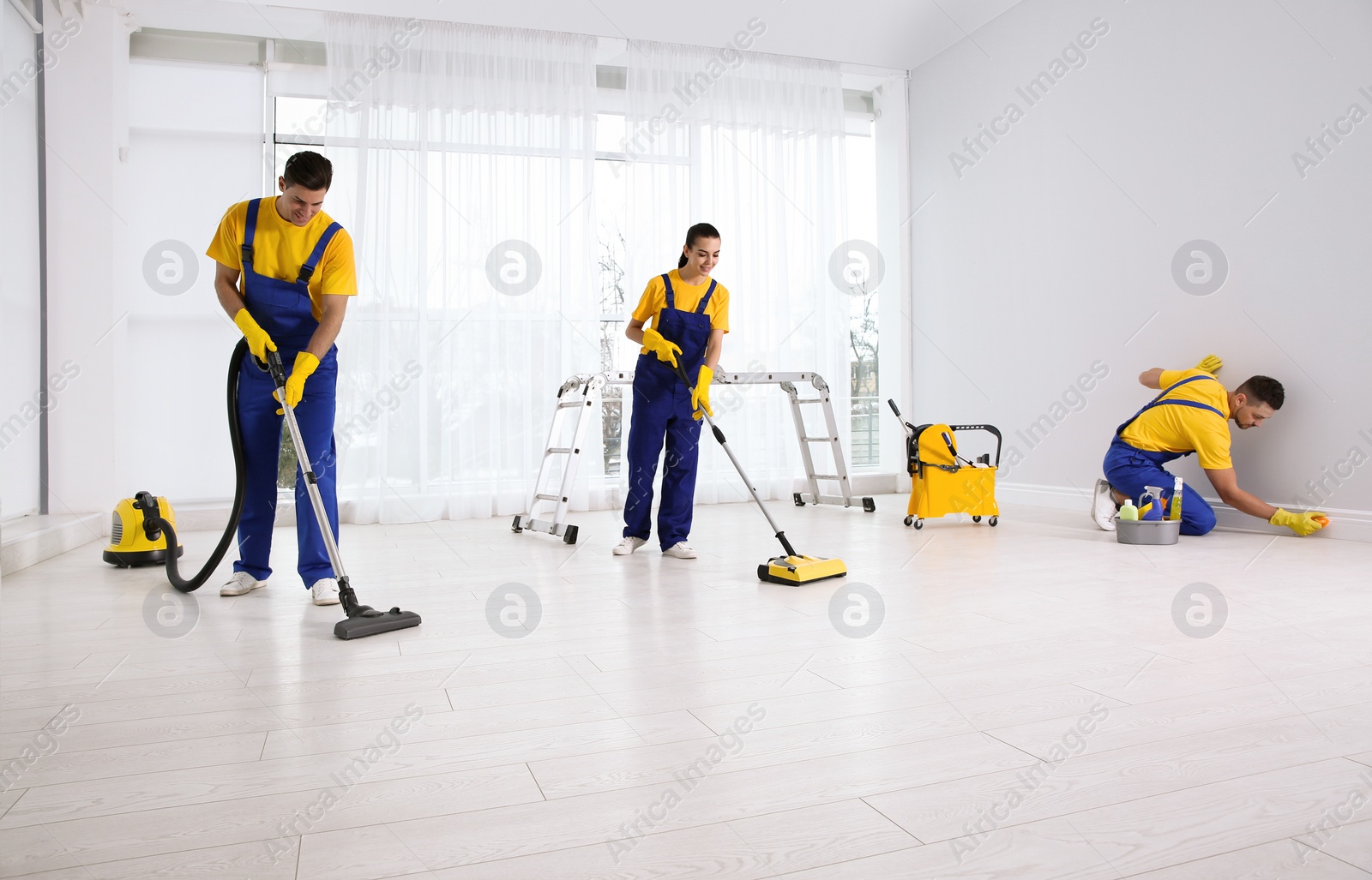 Photo of Team of professional janitors cleaning room after renovation