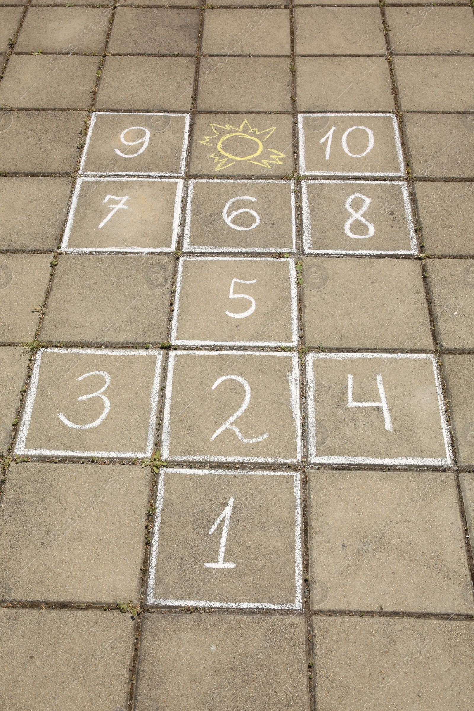 Photo of Hopscotch drawn with white chalk on street tiles outdoors