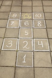 Photo of Hopscotch drawn with white chalk on street tiles outdoors