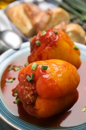 Photo of Delicious stuffed peppers served with green onion on blue plate, closeup