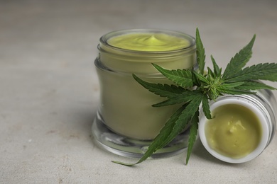 Photo of Jars of hemp cream on grey stone table. Organic cosmetics