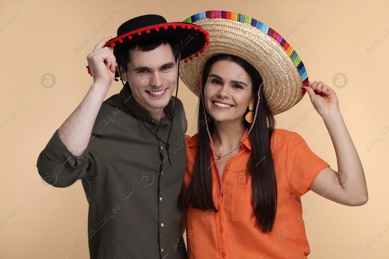 Photo of Lovely couple woman in Mexican sombrero hats on beige background