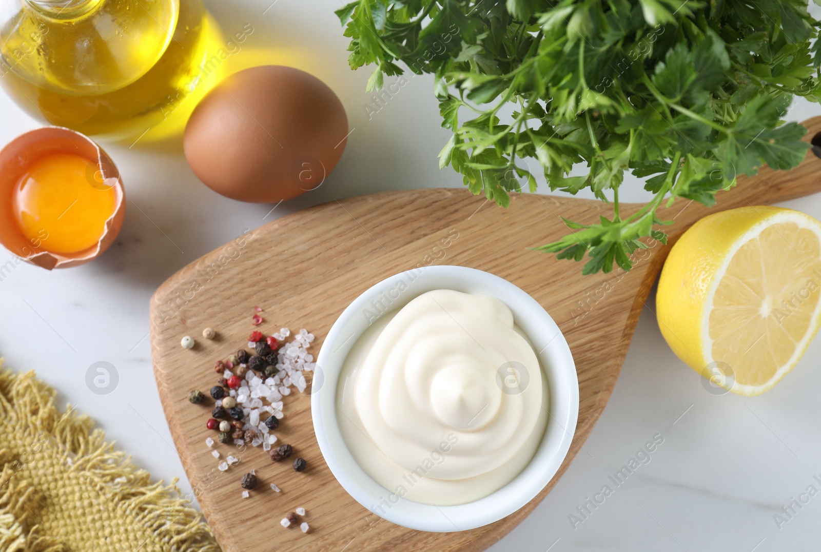 Photo of Tasty mayonnaise sauce in bowl, ingredients and spices on white table, flat lay