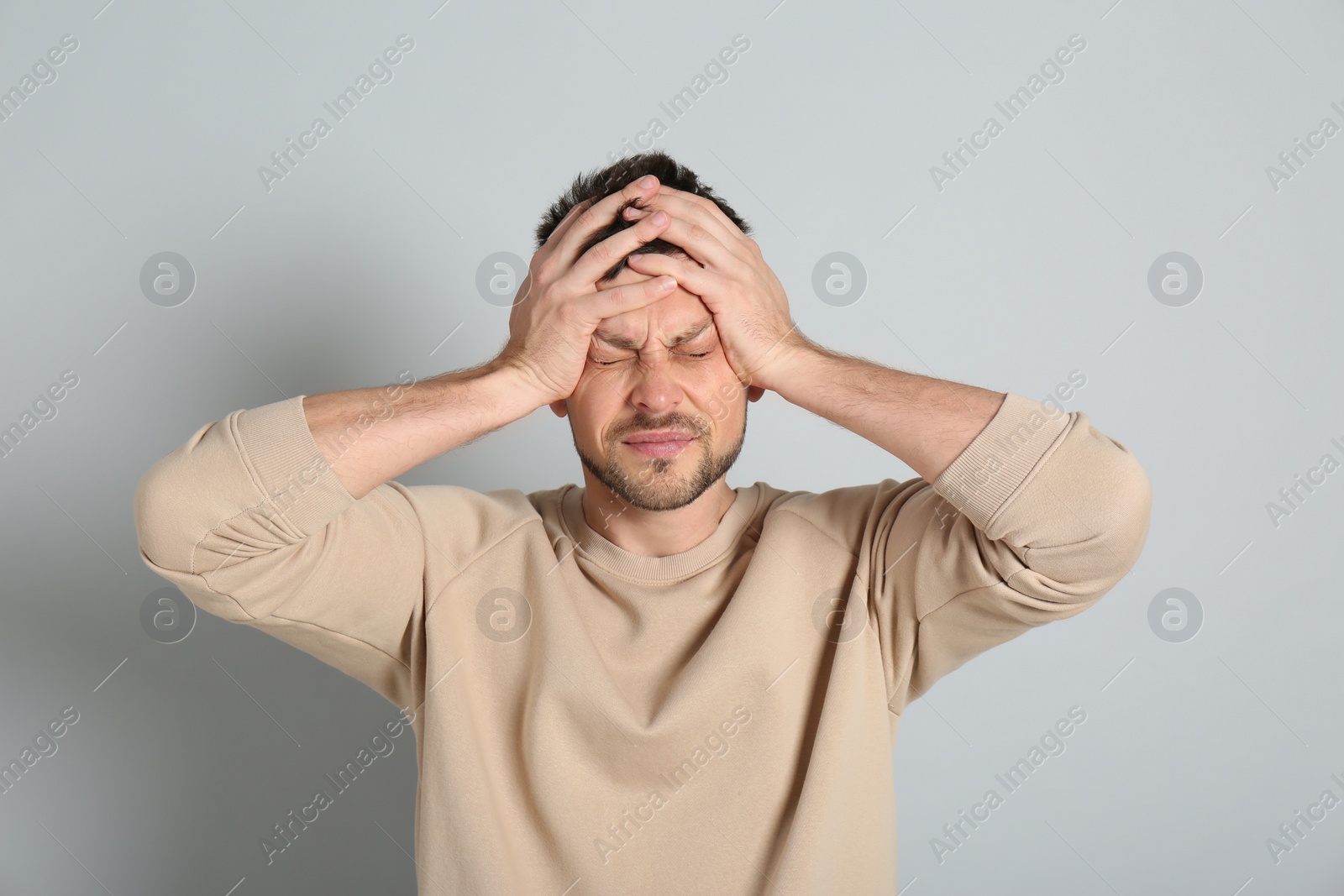 Photo of Man suffering from terrible migraine on light grey background