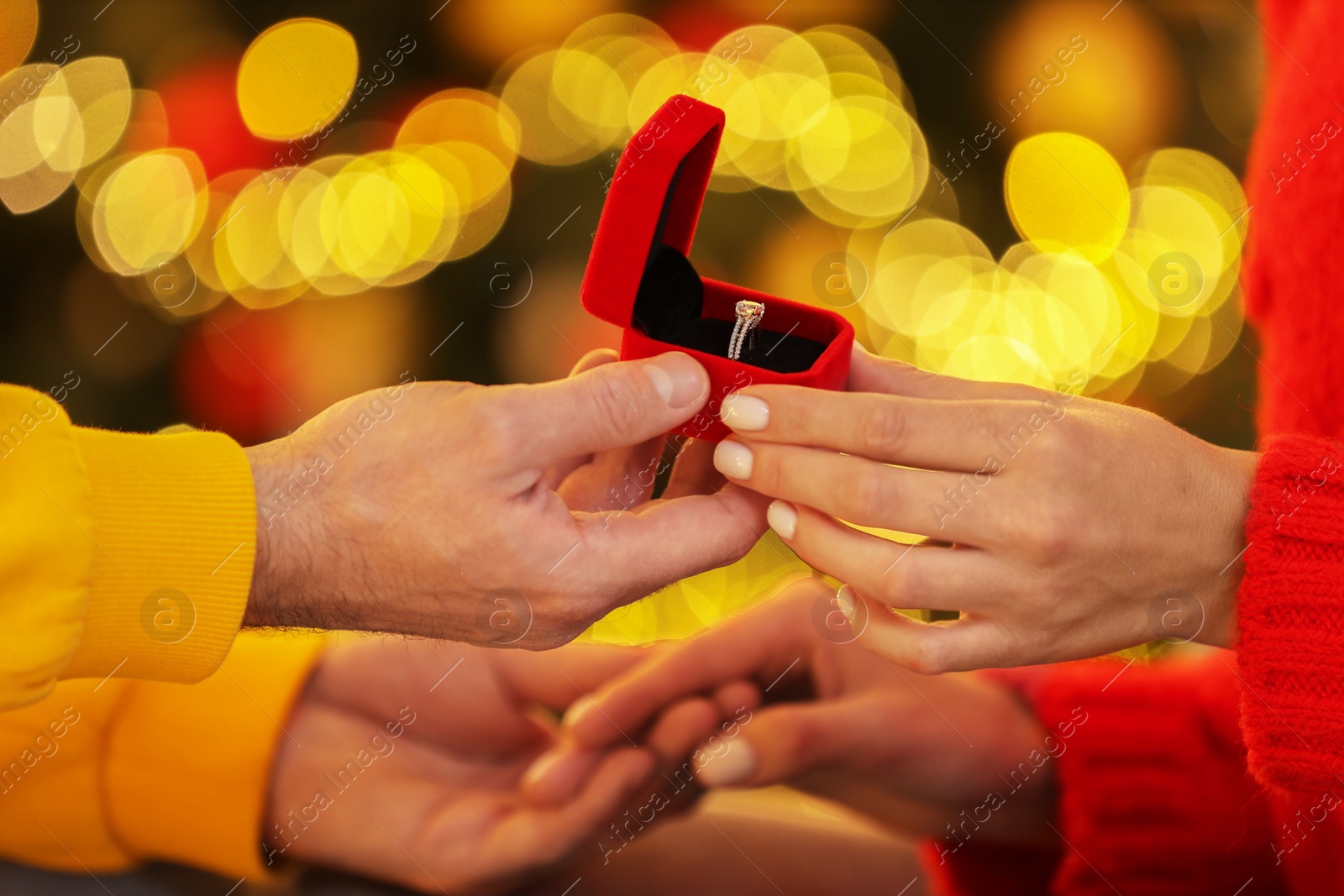 Photo of Making proposal. Man putting engagement ring on his girlfriend's finger against blurred lights, closeup