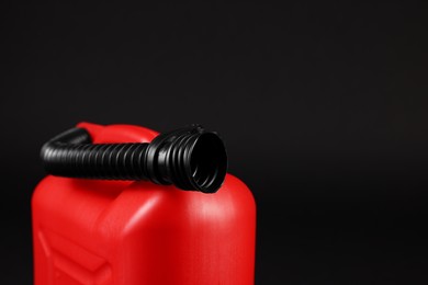 Photo of New red plastic canister on black background, closeup. Space for text