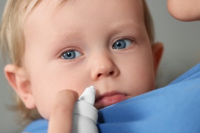 Photo of Mother helping her baby to use nasal spray, closeup