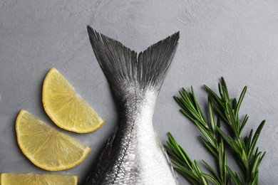 Fresh raw dorado fish, lemon slices and rosemary on grey table, flat lay