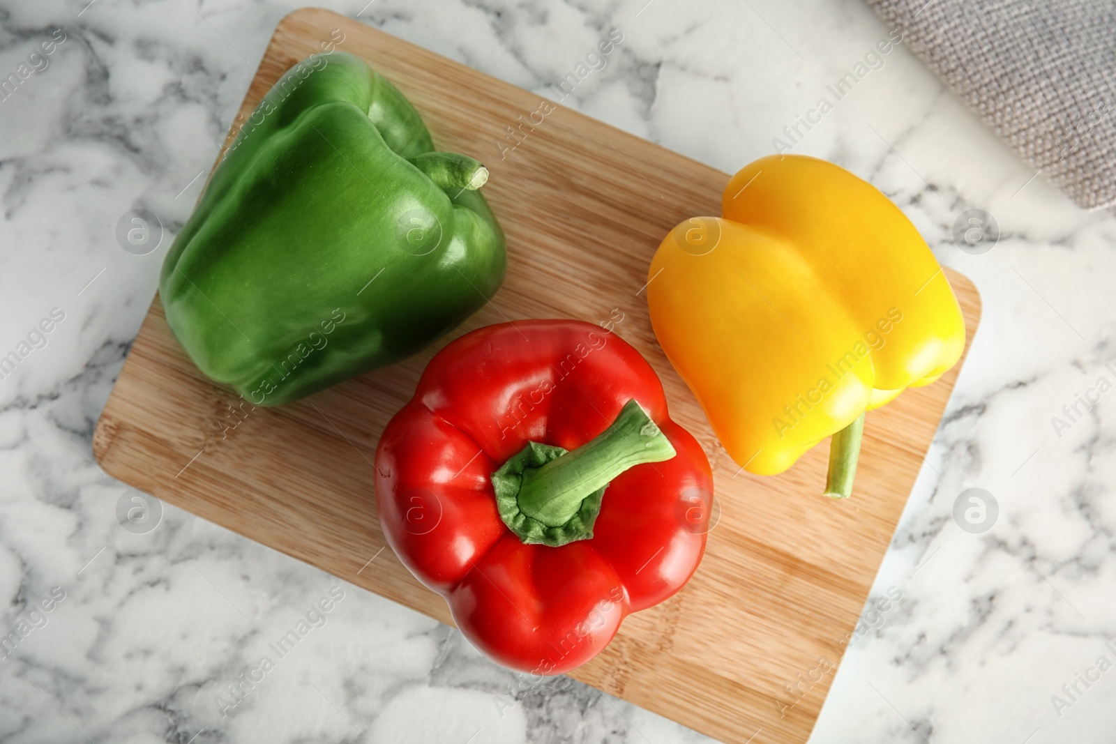 Photo of Wooden board with ripe paprika peppers on marble background, top view