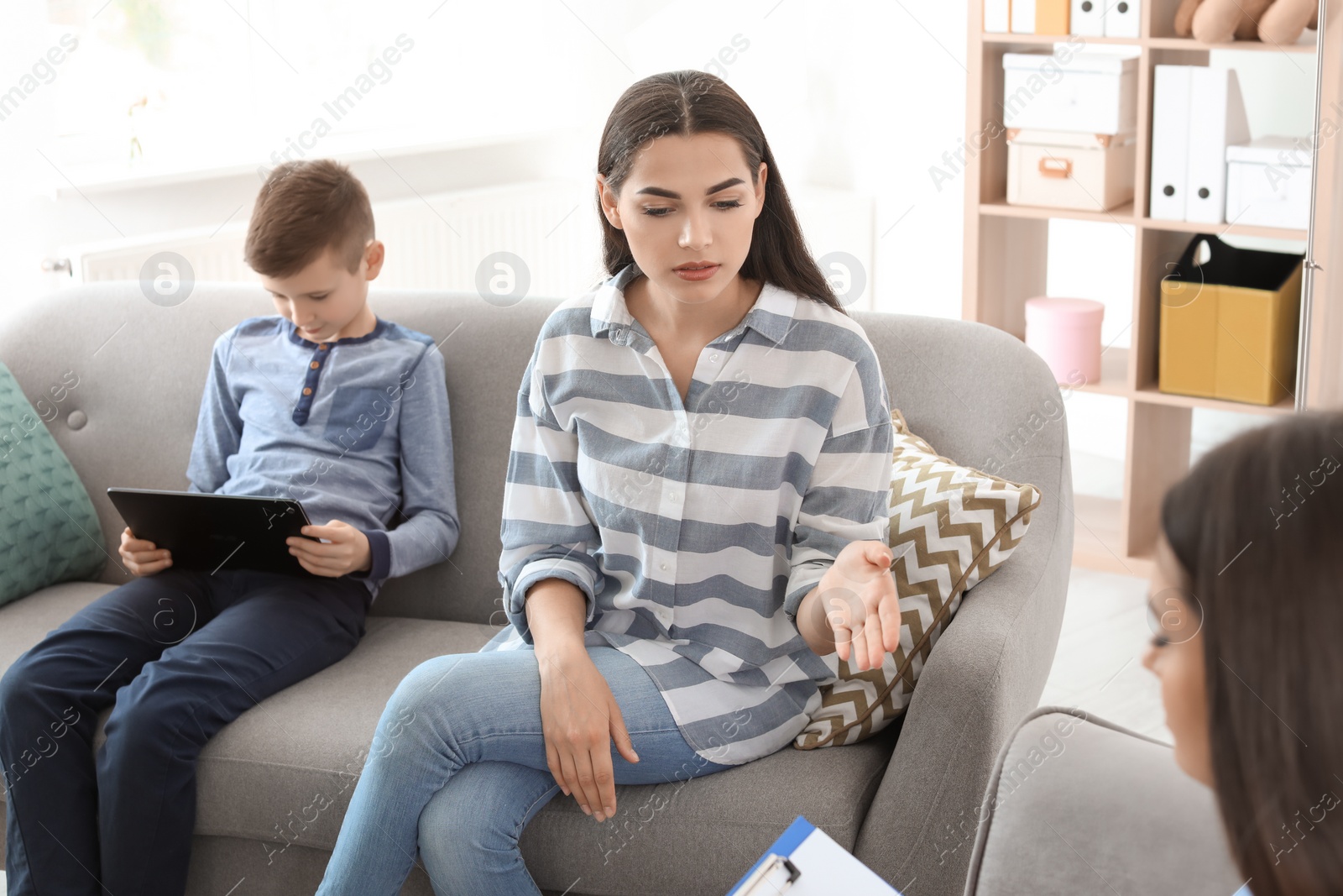 Photo of Young woman and her son visiting child psychologist in office. Computer addiction