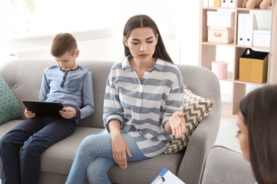 Young woman and her son visiting child psychologist in office. Computer addiction