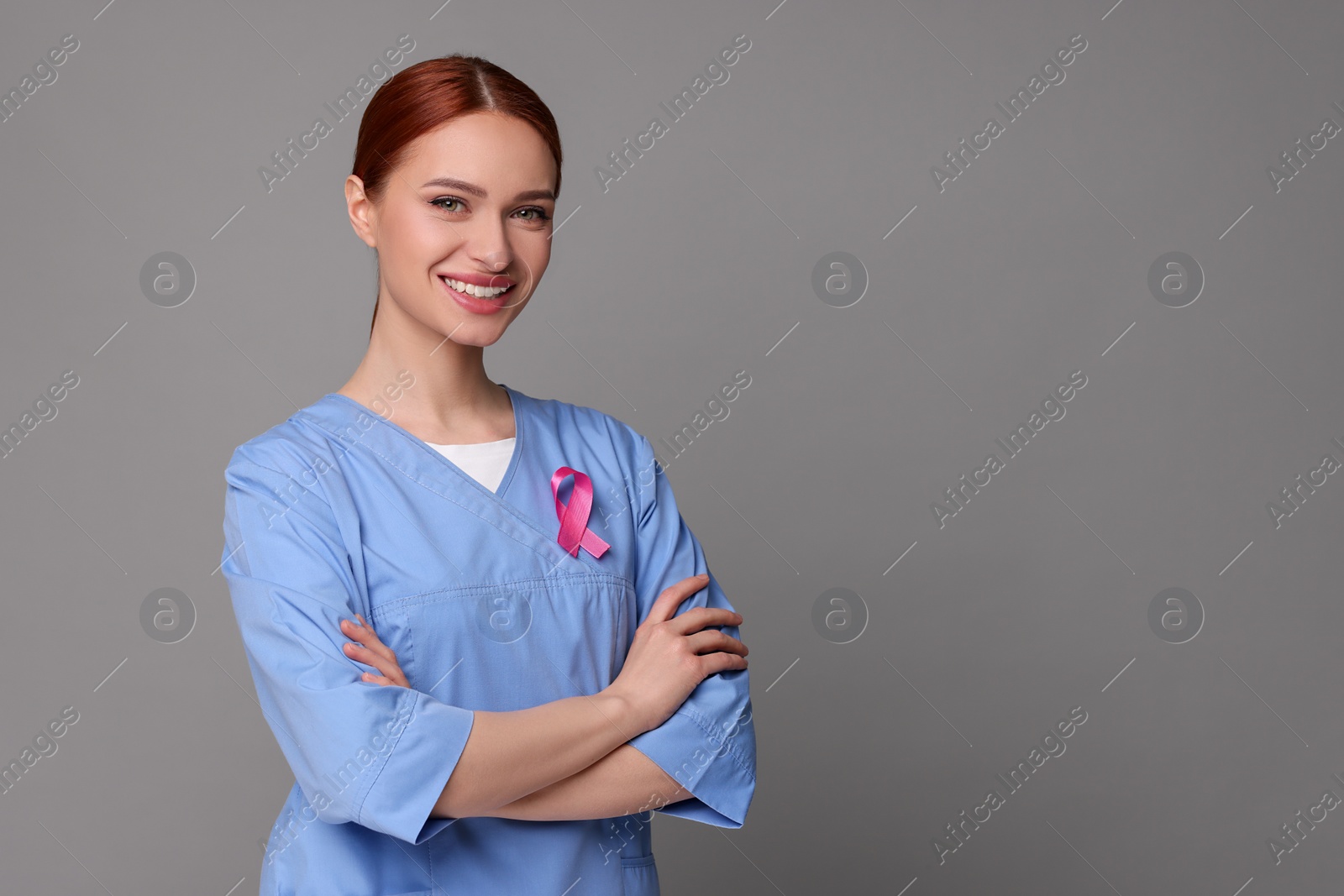 Photo of Mammologist with pink ribbon on gray background, space for text. Breast cancer awareness