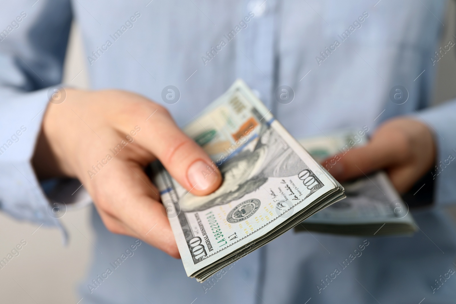 Photo of Woman counting dollar banknotes on light background, closeup