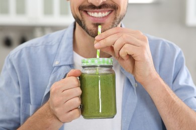 Photo of Happy man drinking delicious fresh smoothie indoors, closeup