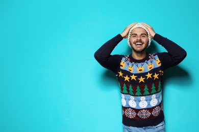 Photo of Young man in Christmas sweater and knitted hat on color background. Space for text