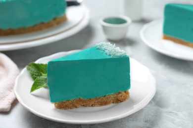 Photo of Piece of tasty spirulina cheesecake on grey table