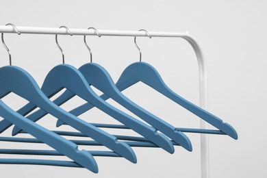 Photo of Empty clothes hangers on metal rack against light background, closeup