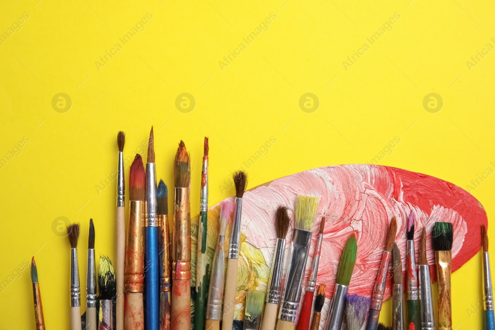 Photo of Different paint brushes and palette on color background, top view with space for text