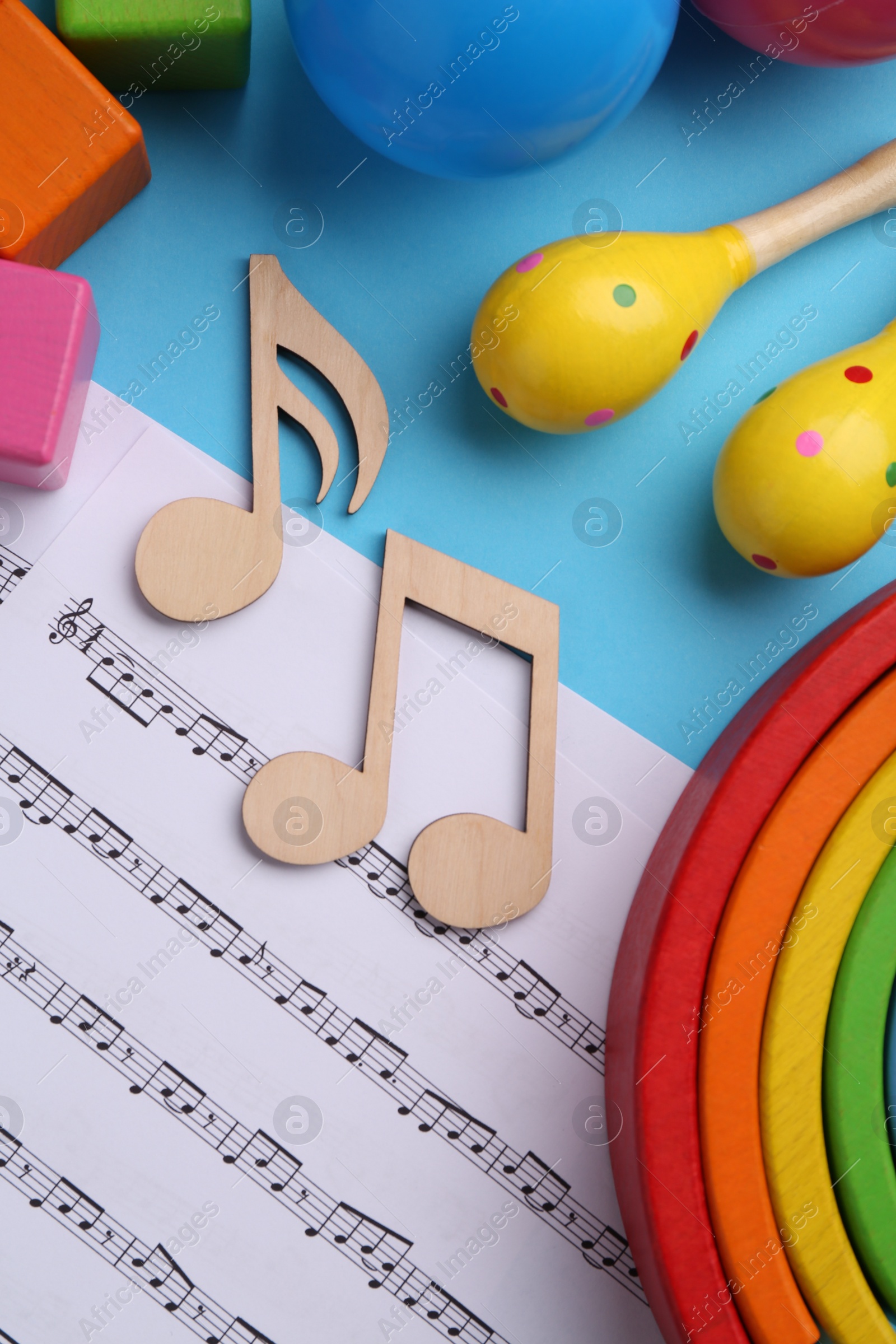Photo of Tools for creating baby songs. Flat lay composition with wooden notes and maracas on light blue background