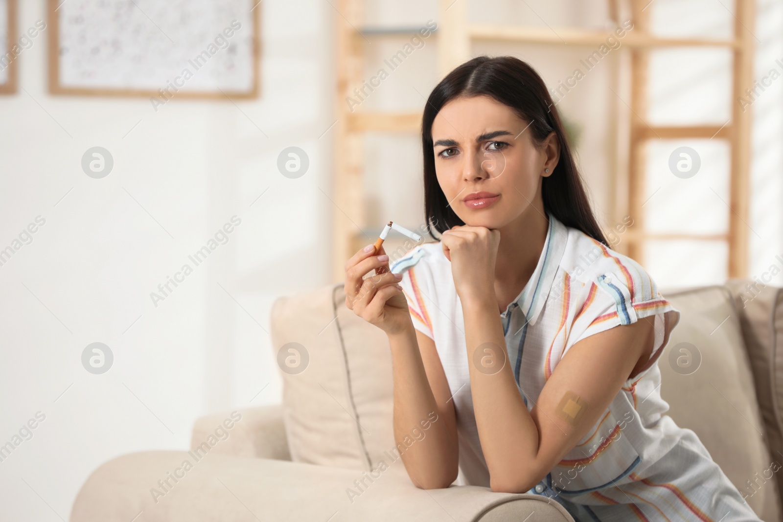 Photo of Emotional young woman with nicotine patch and cigarette at home