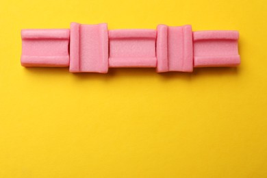 Photo of Tasty pink chewing gums on yellow background, flat lay. Space for text