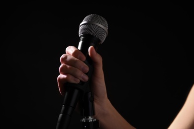 Photo of Woman holding microphone on black background, closeup