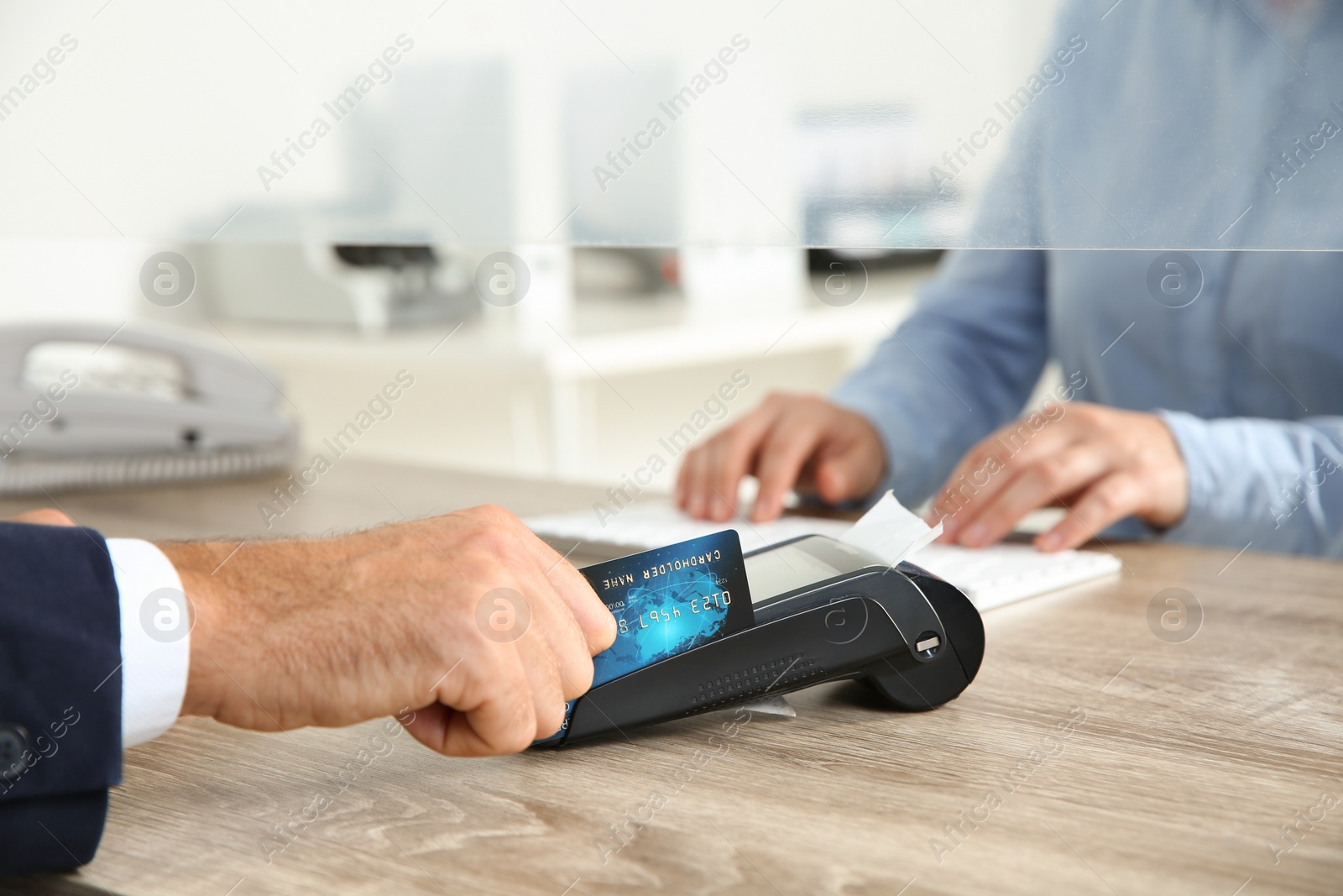 Photo of Man using bank terminal for credit card payment at cash department window, closeup