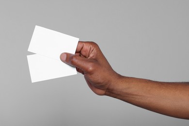 Photo of African American man holding paper cards on grey background, closeup. Mockup for design