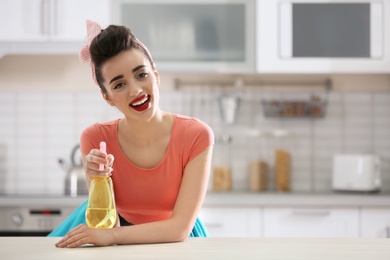 Funny young housewife with detergent in kitchen