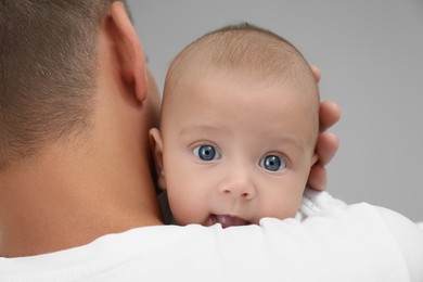 Photo of Father holding his cute baby on grey background, closeup