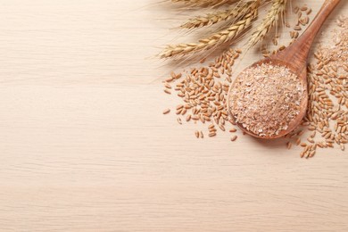 Photo of Wheat bran, kernels and spikelets on wooden table, flat lay. Space for text