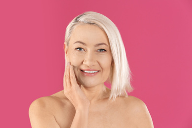 Portrait of beautiful mature woman on pink background