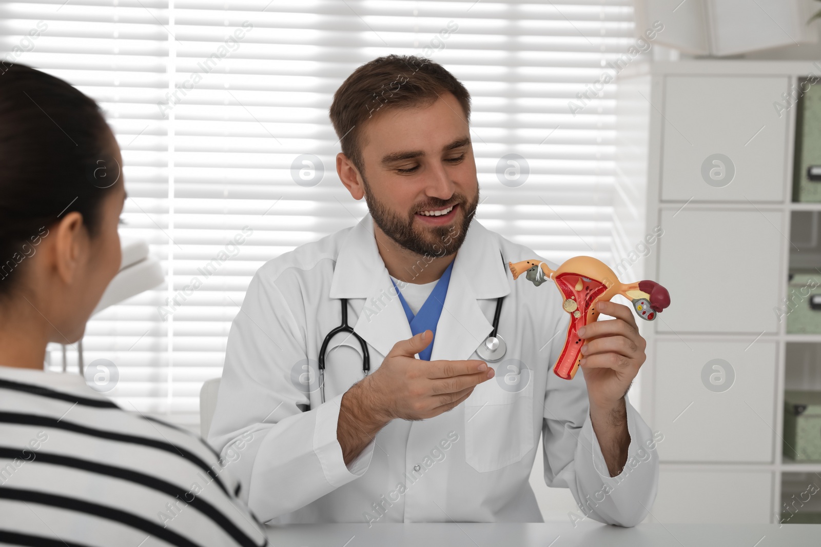 Photo of Gynecologist demonstrating model of female reproductive system to young woman in clinic