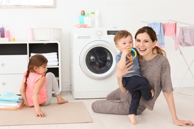Photo of Housewife with little children in laundry room