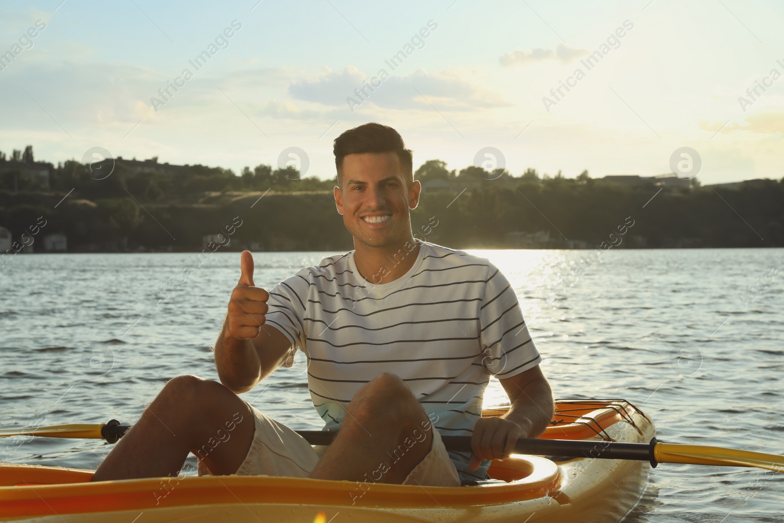 Photo of Happy man showing thumb up while kayaking on river. Summer activity