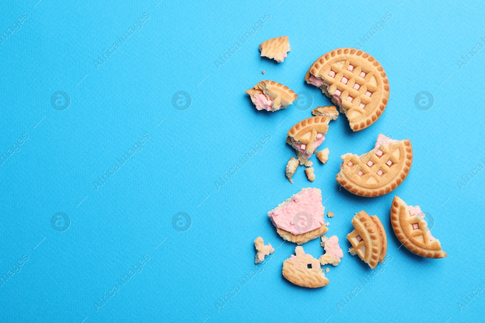 Photo of Tasty sandwich cookies with cream on light blue background, flat lay. Space for text
