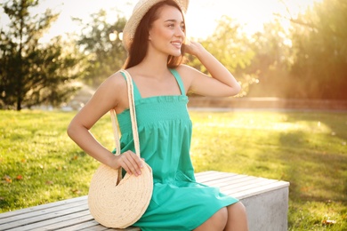 Photo of Young woman with stylish straw bag in park