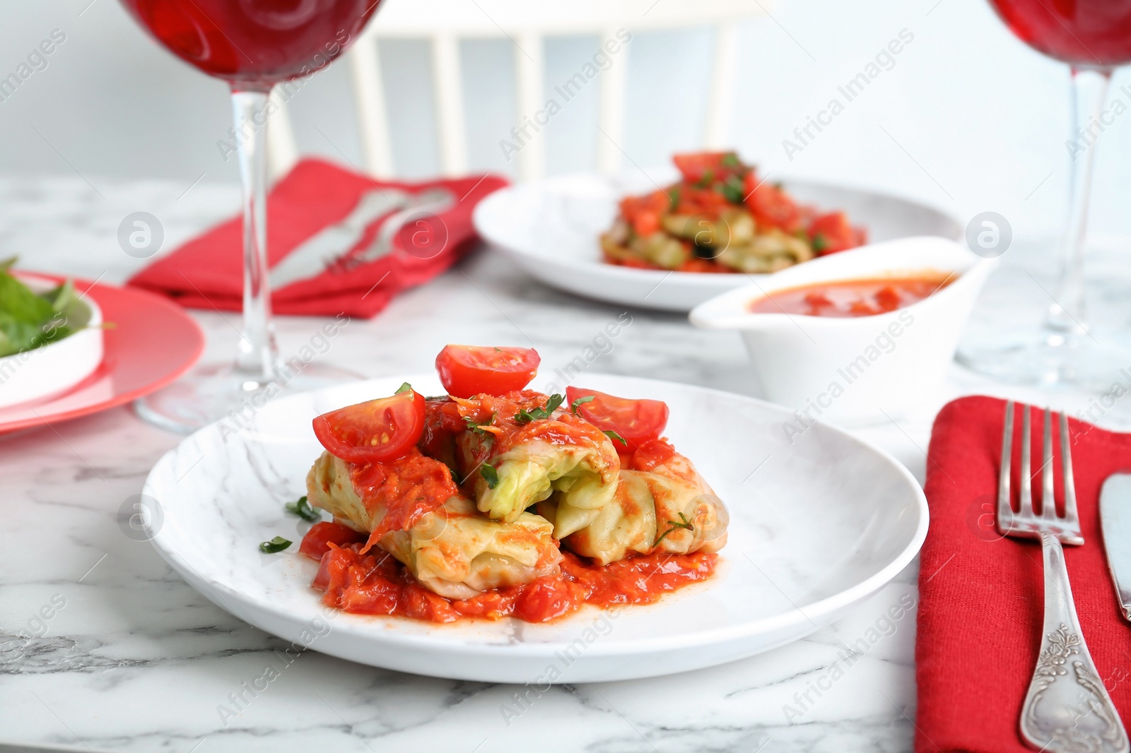 Photo of Plate with stuffed cabbage leaves in tomato sauce on table