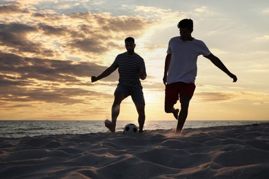 Photo of Friends playing football on beach at sunset