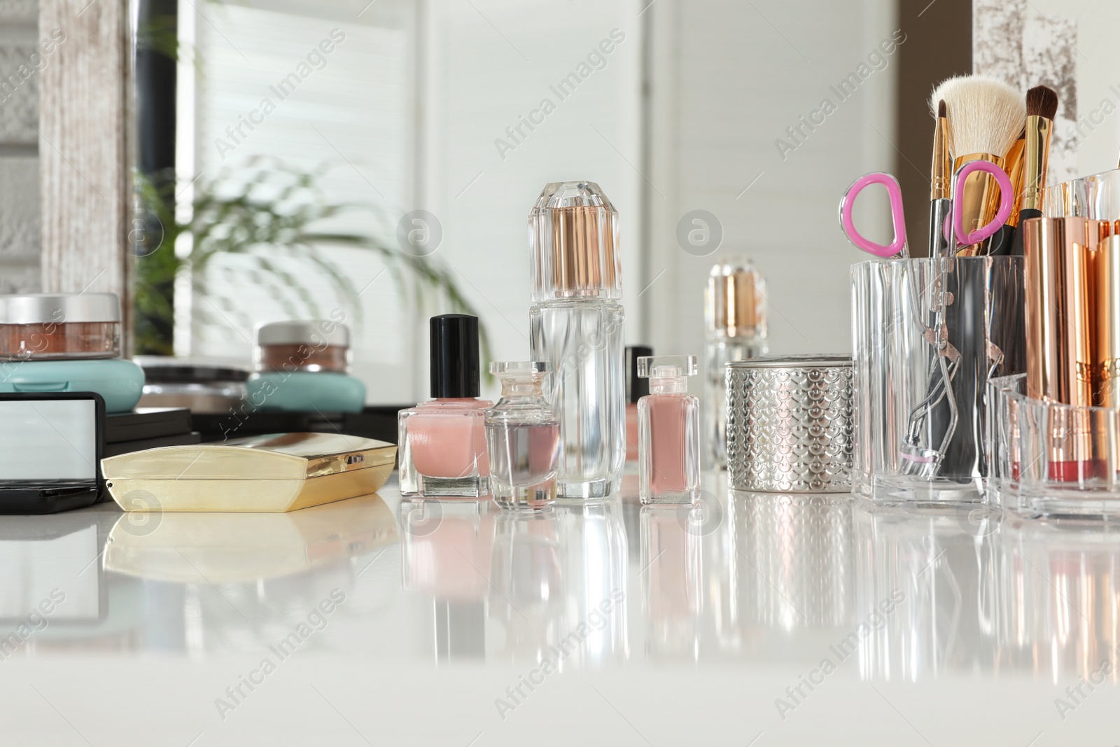 Photo of Luxury makeup products and accessories on dressing table with mirror