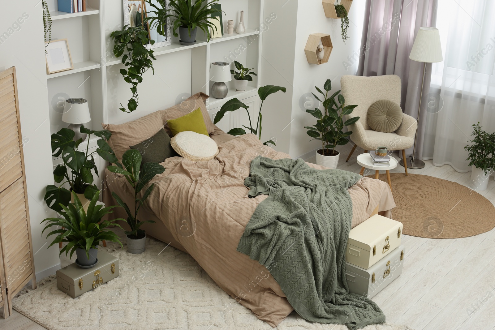 Photo of Stylish bedroom with comfortable bed and different houseplants. Interior design