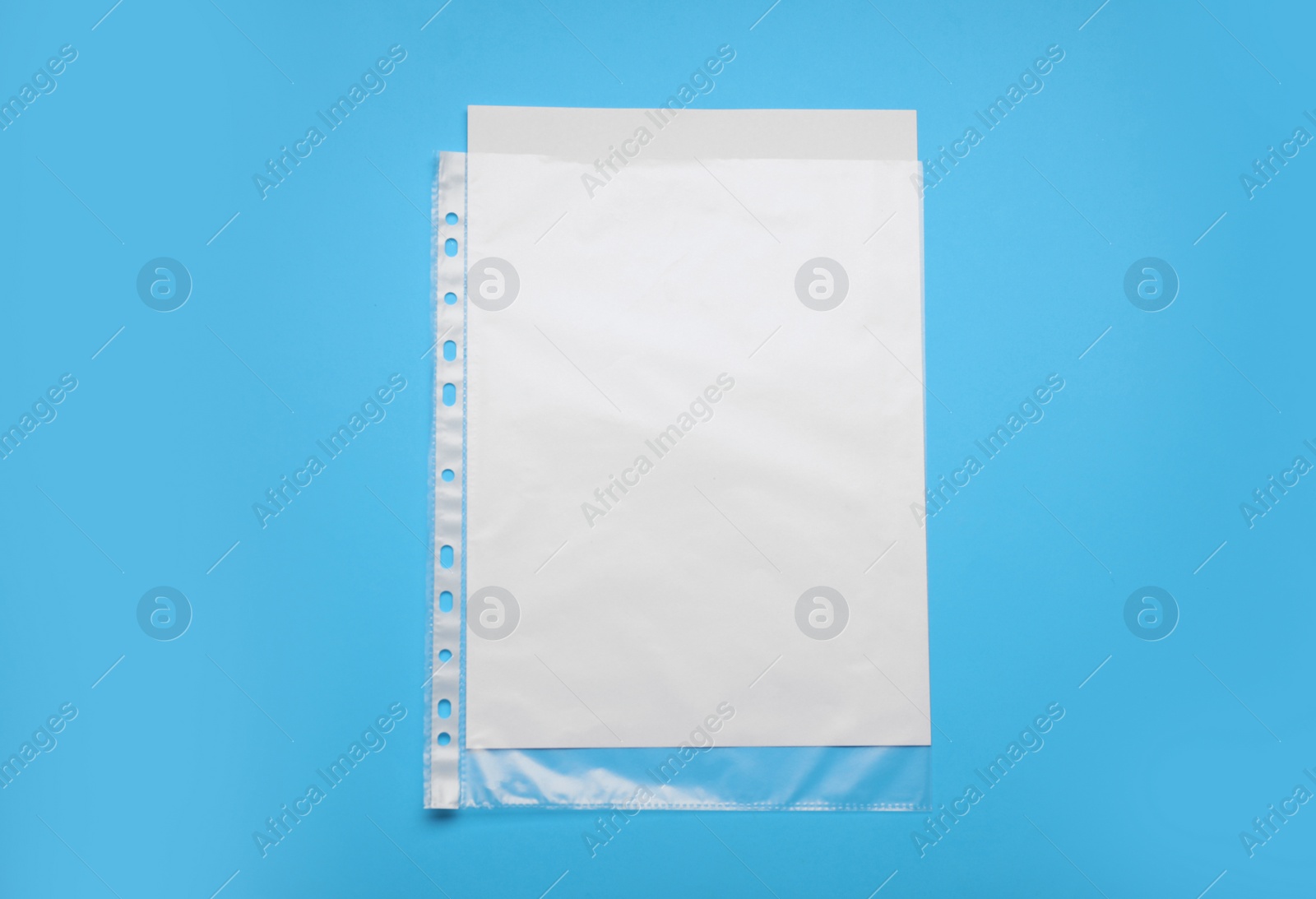 Photo of Punched pocket with paper sheet on light blue background, top view. Space for text