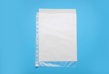 Photo of Punched pocket with paper sheet on light blue background, top view. Space for text