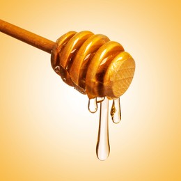 Image of Natural honey dripping from dipper on pale orange background