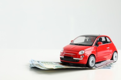 Toy car and money on white background, space for text. Vehicle insurance