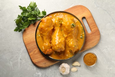 Photo of Tasty chicken curry and ingredients on grey textured table, flat lay